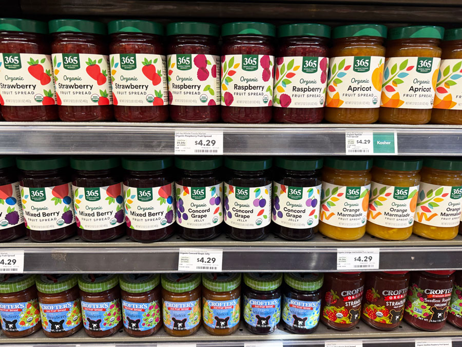 365 Organic Strawberry, Raspberry, Apricot, Mixed Berry, and Concord Grape spreads displayed in Whole Foods Market.
