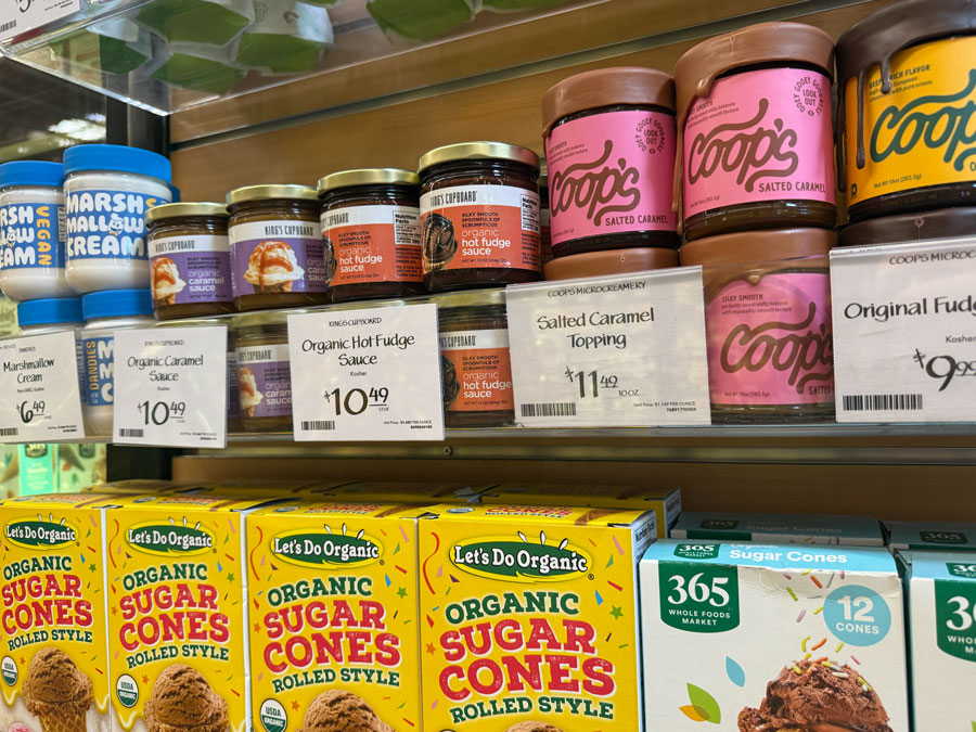Boxes of 365 Organic Sugar Cones displayed alongside caramel and hot fudge sauces on store shelves.