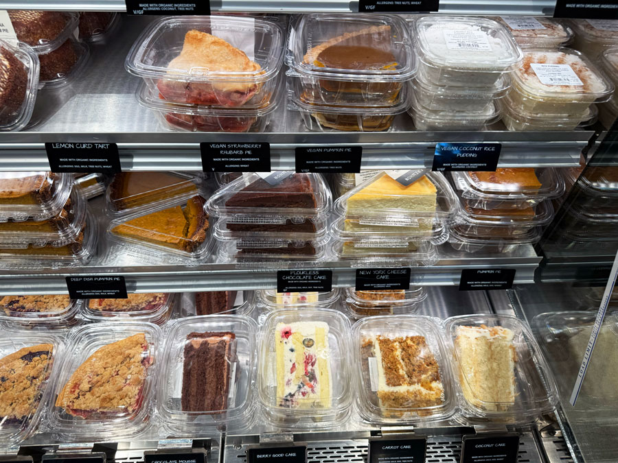 Individual slices of chocolate cake, cheesecake, and pies in Erewhon's dessert case.